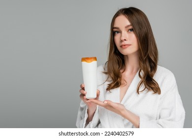 young woman with shiny hair holding bottle with shampoo isolated on grey - Shutterstock ID 2240402579