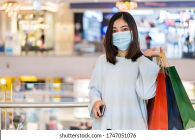 Young Woman Shopping With Bag At Mall And Her Wearing Medical Mask For Prevention From Coronavirus (Covid-19) Pandemic. New Normal Concepts