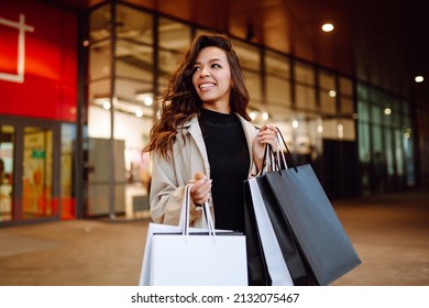 Young woman with shopping bags near mall. Spring Style. Consumerism, purchases, shopping, lifestyle, sale concept.