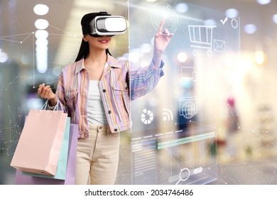 Young Woman With Shopping Bags Using Virtual Reality Headset In Simulated Store