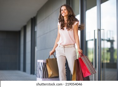 Young Woman With Shopping Bags Walking Out From Shop