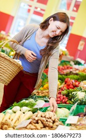 Young Woman With Shopping Basket Buys Fresh Vegetables In Health Food Store