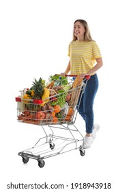 Young woman with shopping cart full of groceries on white background