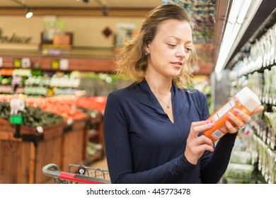 Young woman shopping in the fresh juice section at the grocery store.