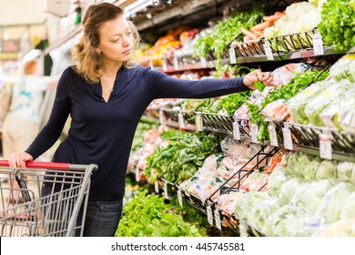 Young woman shopping in the fresh produce section at the grocery store. - Shutterstock ID 445745581