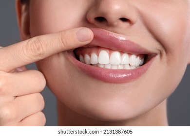 Young woman showing healthy gums on grey background, closeup