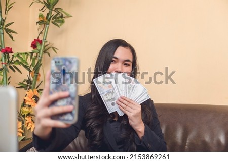 A young woman showing her achievements. Taking a photo flaunting lots of cash from hard work. Earned a lot of money.
