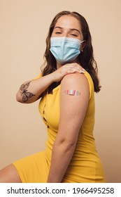 Young Woman Showing Her Arm With Bandage After Vaccination. Female Wearing Protective Face Mask After Getting Covid Vaccine.