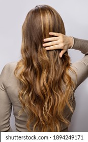 Young woman showing her beautiful hair after dyeing and styling in a professional salon