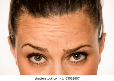 Young Woman Showing Her Forehead Wrinkles With Her Fingers On A White Background