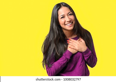 Young woman showing her heartfelt gratitude and thanks clasping her hands to her heart with a pleased smile on, Before Candy Background