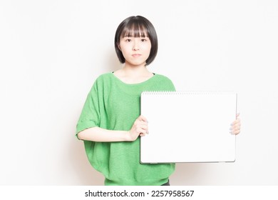 Young woman showing a large sketchbook. - Shutterstock ID 2257958567