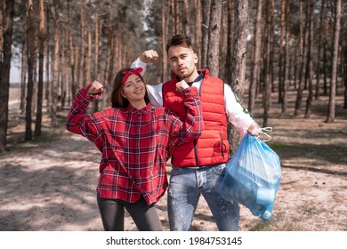 Young Woman Showing Power Gesture And Standing Near Man Holding Trash Bag 