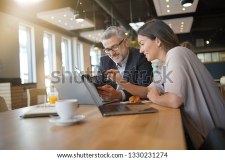 Young woman showing salesman stats on cellphone during informal meeting