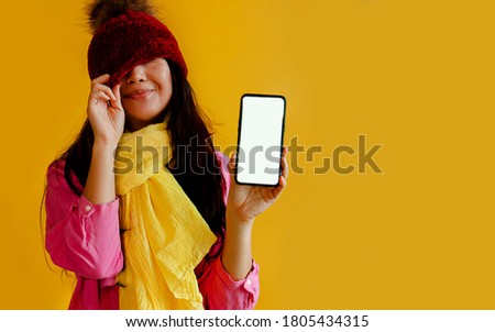 Young Woman Showing Smart Phone Display Screen And Copy Space For Text On Yellow Background.