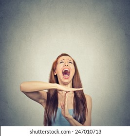 Young woman showing time out hand gesture, frustrated screaming to stop isolated on grey wall background. Too many things to do. Human emotions face expression reaction 