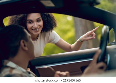 Young Woman Showing The Way To A Car Driver And Smiling