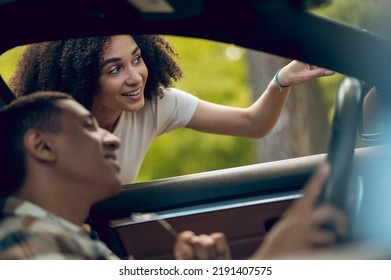 Young Woman Showing The Way To A Car Driver And Smiling