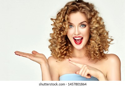 Young woman shows and advertises some product .Beautiful girl  pointing to the side . Presenting your services. Expressive facial expressions emotions