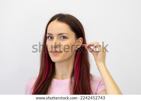 Young woman shows how to correctly insert earplugs into noise protection.