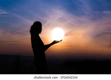 Young Woman As Silhouette And Hand Holding The Sun.