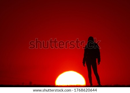 Young woman silhouette at sunset on a farm.
Concept of nature and beauty. Orange sunset. Girl silhuette at sunset.