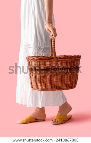 Young woman with silver bracelet and wicker basket on pink background