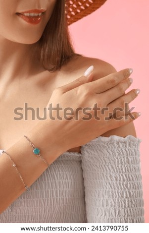 Young woman with silver bracelets on pink background, closeup
