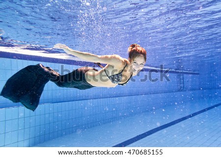 Young woman in siren costume swimming in the pool