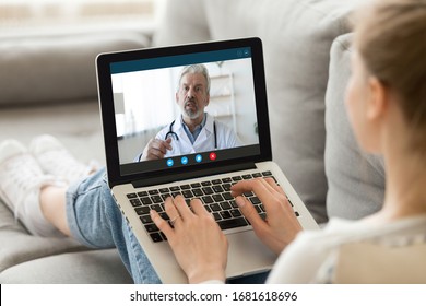 Young woman sit on couch at home have video call with doctor use wireless internet connection on laptop, female patient talk consult with physician online on webcam conference on computer