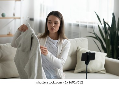 Young woman sit on couch at home record unpacking clothing haul shopping online on internet, millennial female client shopaholic influencer demonstrate show clothes on camera, shoot fashion vlog - Powered by Shutterstock