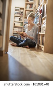 Young Woman Sit On The Floor Reads A Book Near Home Library