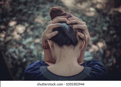 A young woman sits alone and uses her hand to catch her head because of a headache from the stress of her business failing and losing motivation and inspiration from someone.