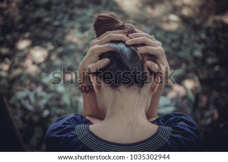 A young woman sits alone and uses her hand to catch her head because of a headache from the stress of her business failing and losing motivation and inspiration from someone.