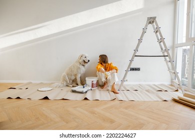 Young woman sits with her dog in room while making repairing in apartment. Repair and house renovation concept, friendship with pet - Powered by Shutterstock