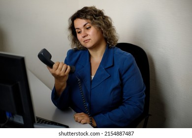 A Young Woman Sits At An Office Desk In Perplexity, Can't Get Through On The Phone. Telemarketer, Telemarketing Agent, Office Employee.