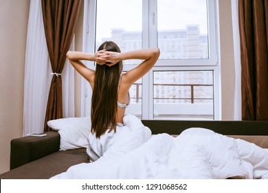 young woman sits on the bed after waking up - Shutterstock ID 1291068562