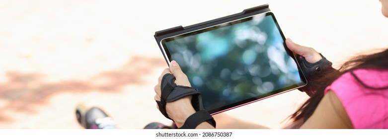 Young Woman Sits On Park Bench With Tablet And Roller Skates. Remote Work And Education Concept