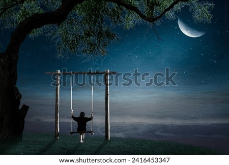 A young woman sits on a swing on a lonely half-moon night.