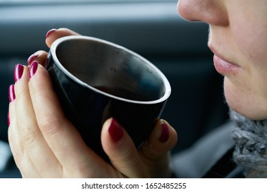 Young woman sits in the trunk of the car and holds a cup of hot drink in her hands - Shutterstock ID 1652485255