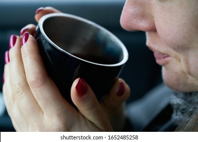 Young woman sits in the trunk of the car and holds a cup of hot drink in her hands - Shutterstock ID 1652485258
