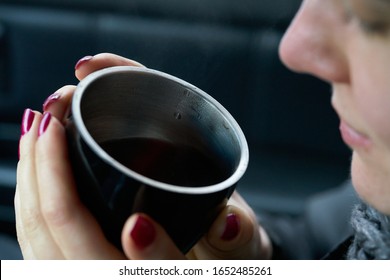 Young woman sits in the trunk of the car and holds a cup of hot drink in her hands - Shutterstock ID 1652485261