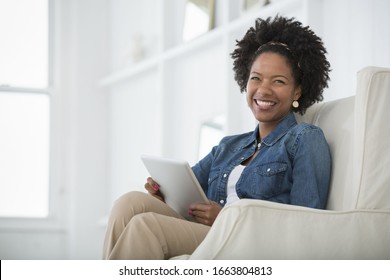 A young woman sitting in an armchair with a digital tablet. An office interior.