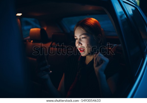 Young woman sitting in back seat of car vehicle\
with mobile phone. Taxi\
concept.