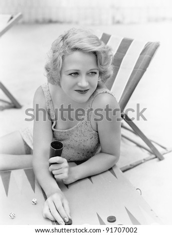 Young woman sitting at the beach playing backgammon