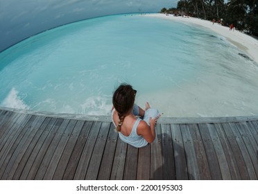 Young Woman Sitting Behind The Beach In Maldives. Photo Taken By Gopro