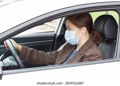 Young Woman Sitting Behind The Wheel Of Car Wearing Mask, Side View.