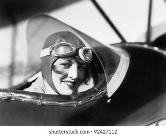 Young woman sitting in a biplane with hat and gargles