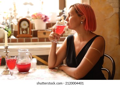 A Young Woman Is Sitting In A Cafe And Drinking Cranberry Juice