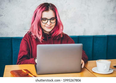 Young Woman Sitting At Caffe, Drinking Coffee And Working On Laptop.